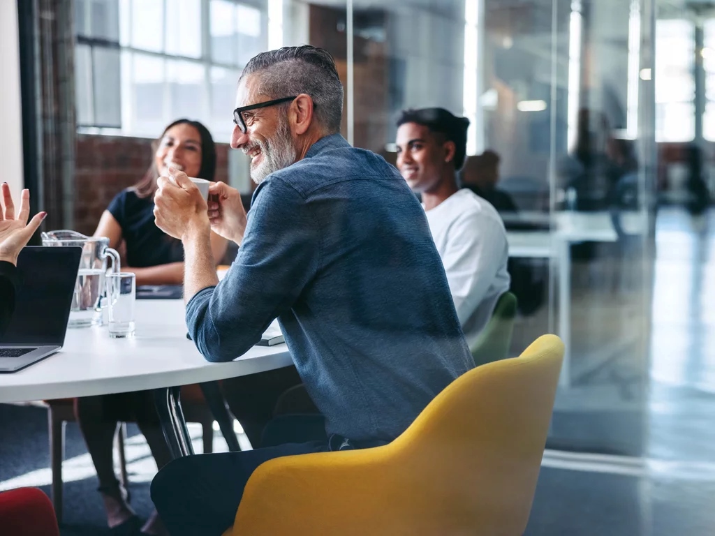 Picture of smiley people having a meeting in a room; ?>